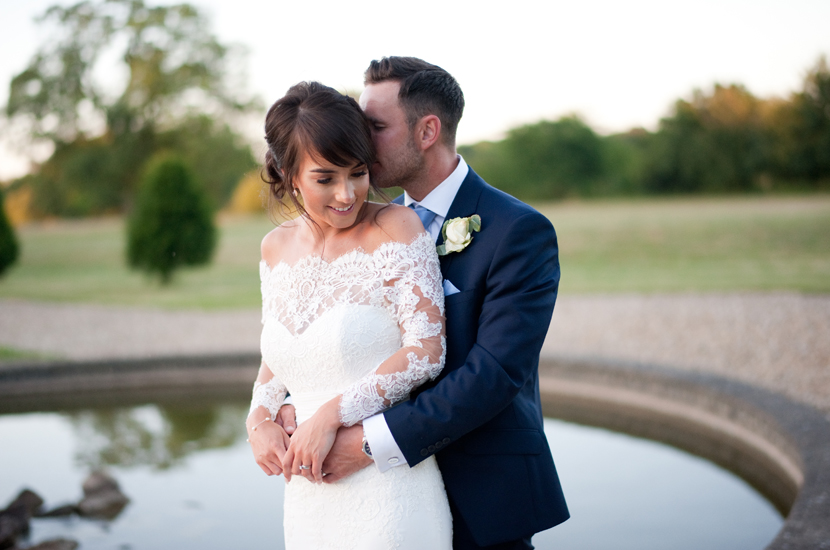 Professional colour photograph of a bride and groom cuddling