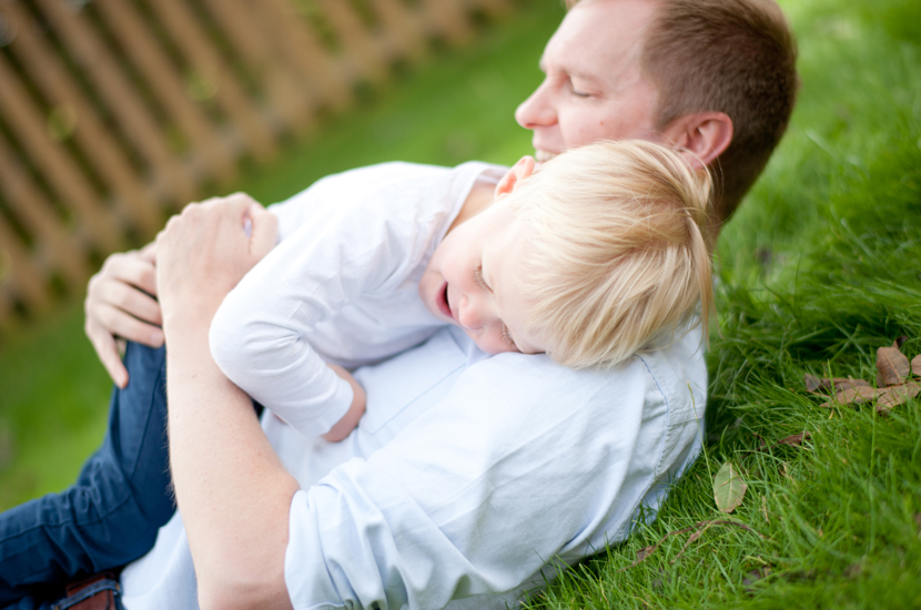 Professional colour photograph of daddy having fun cuddling son 