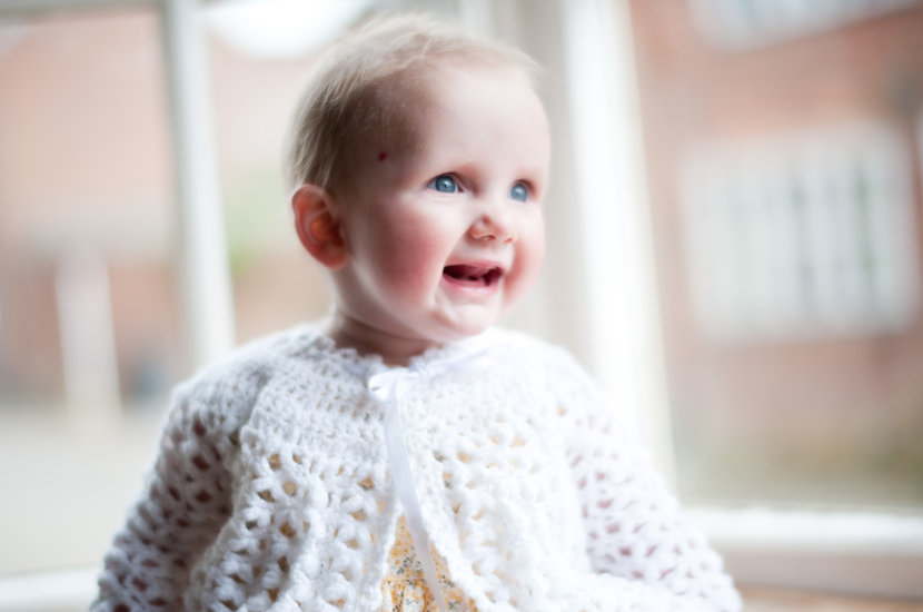 Professional colour photograph of baby girl sitting in a window